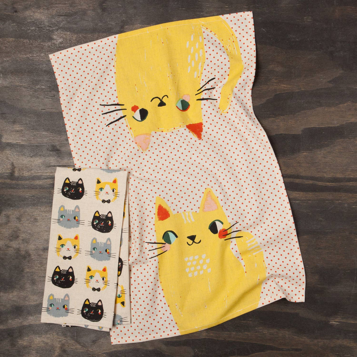 Two yellow cat-themed towels on a wooden surface