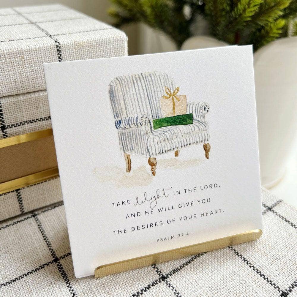 Card with a couch illustration and Christmas-themed text on a checkered surface.