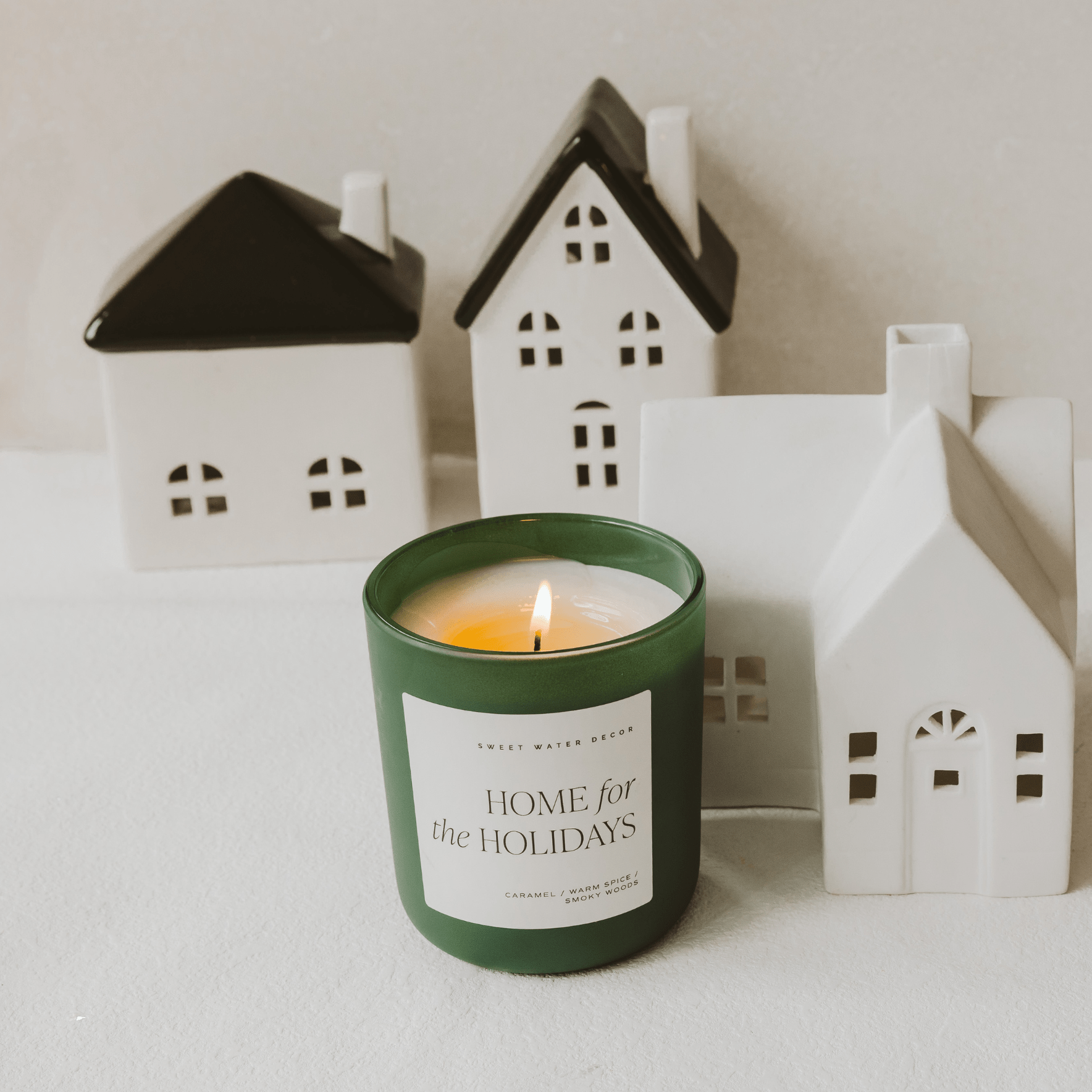 Candle labeled 'Home for the Holidays' with miniature houses in the background