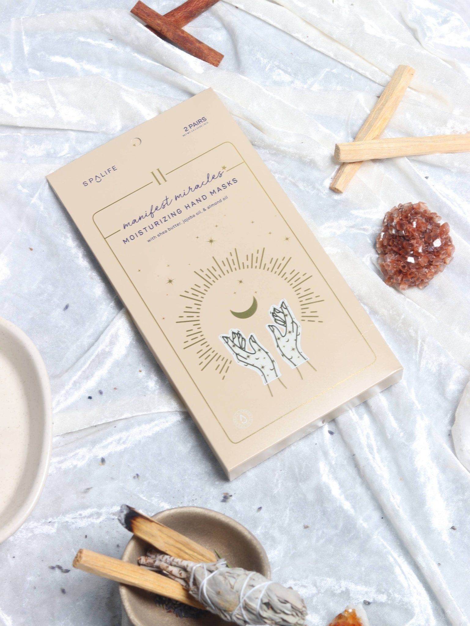 Box of manifest miracles hand wax on a textured surface with crystals and sticks.