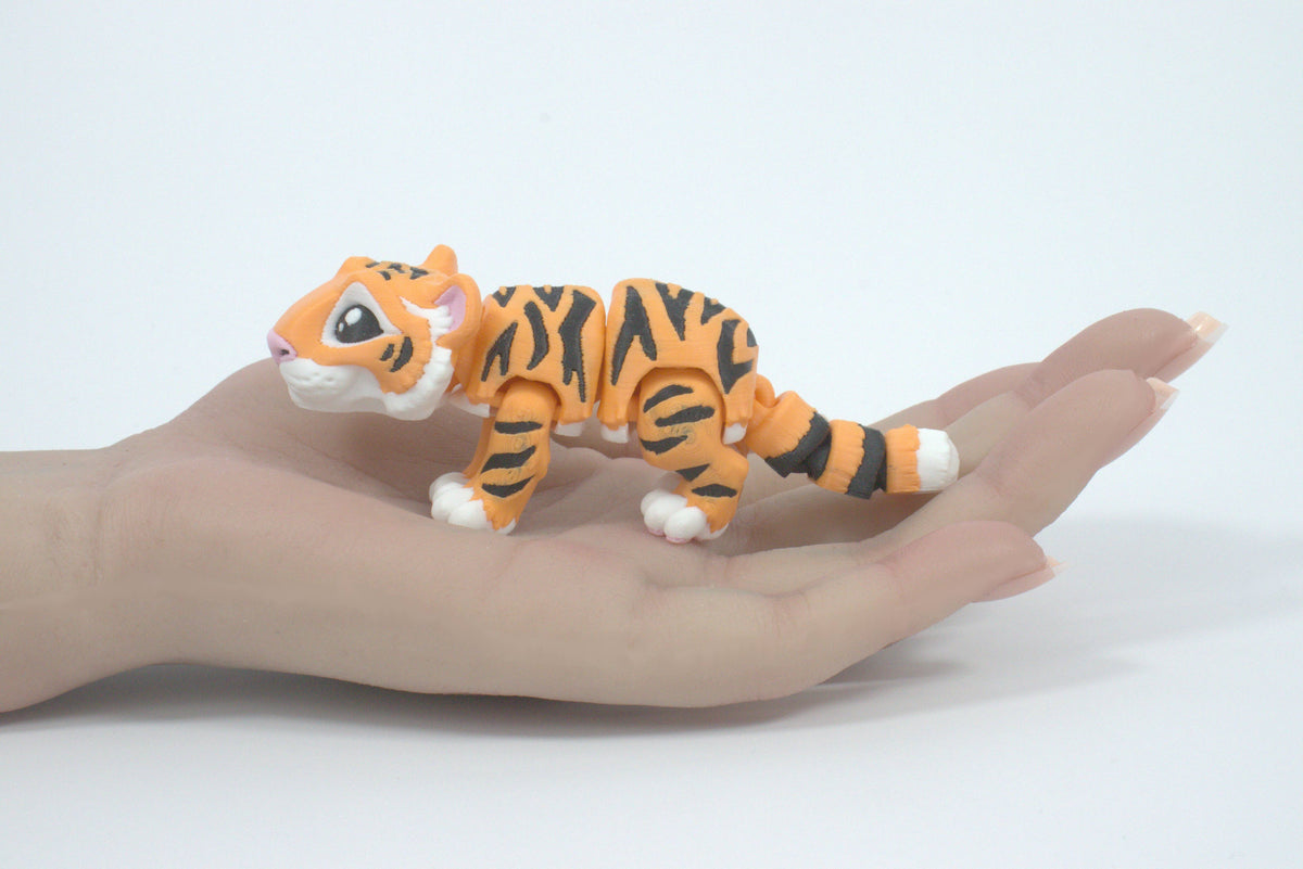 Toy tiger figure on a person's hand against a white background