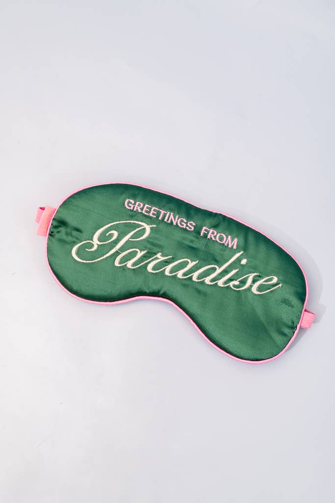 Emerald green satin sleep mask with pink trim, elastic, and 'Greetings From Paradise' embroidery