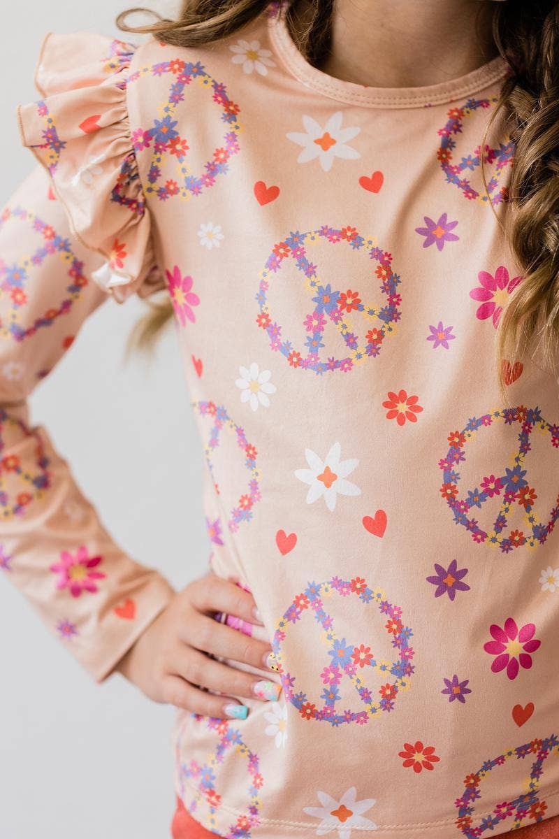 Peach long sleeve girl's top with floral peace sign and ruffle sleeves.