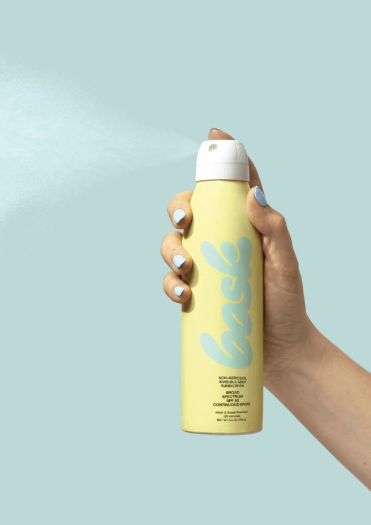 Hand holding a yellow bottle of Bask Aerosol sunscreen against a light blue background