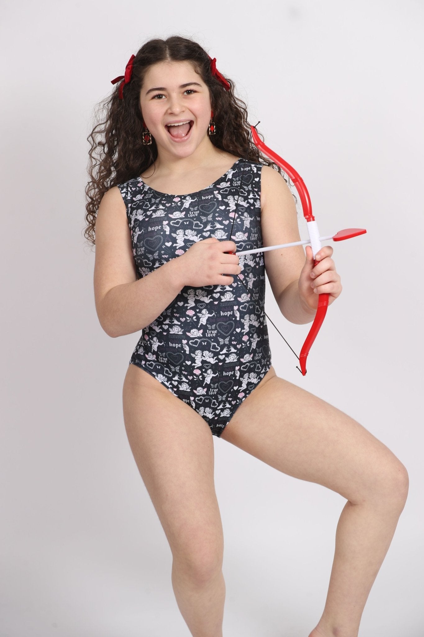 Girl in cupid print leotard holding a bow and arrow.