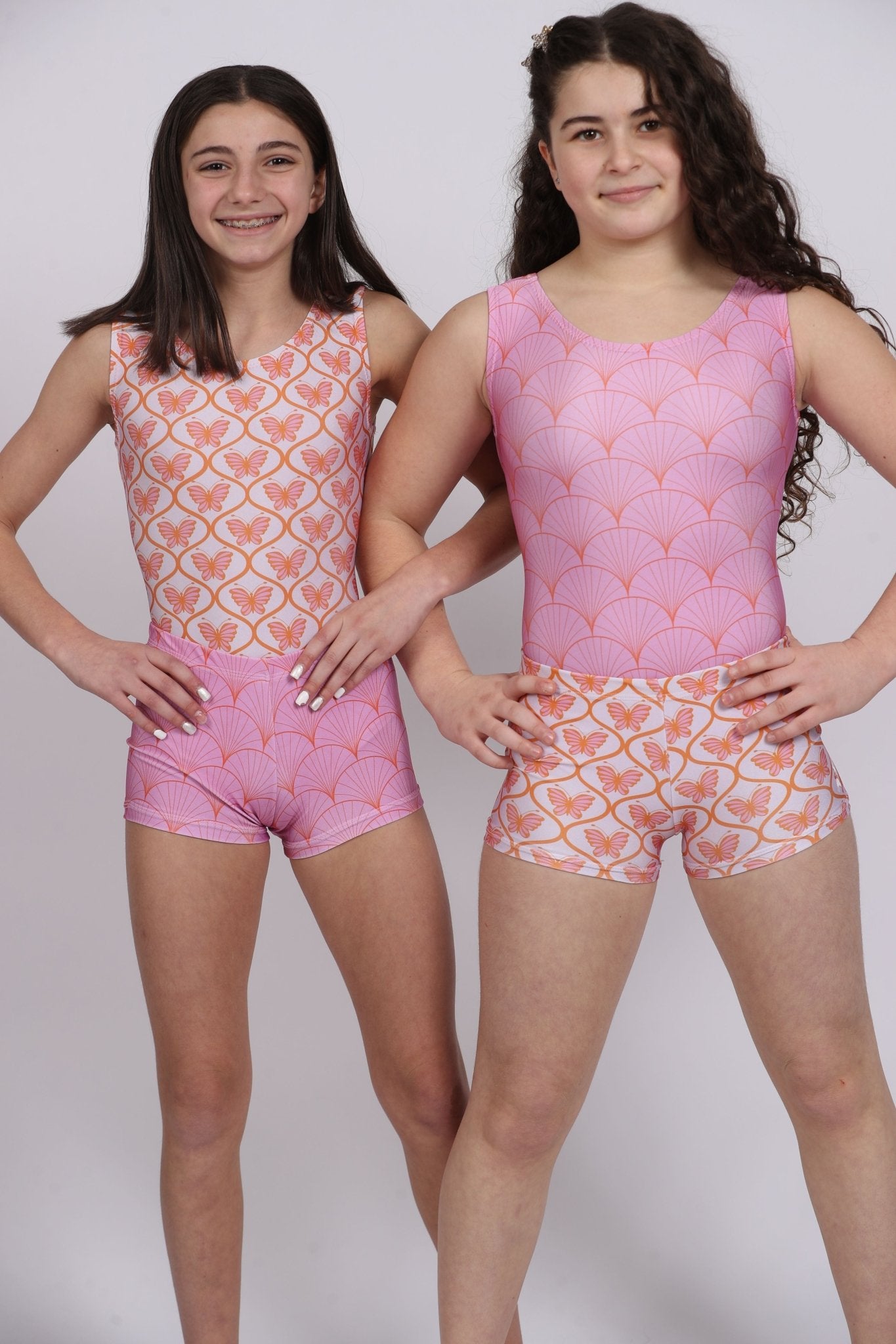 Two girls in pink patterned gymnastics leotards and shorts.