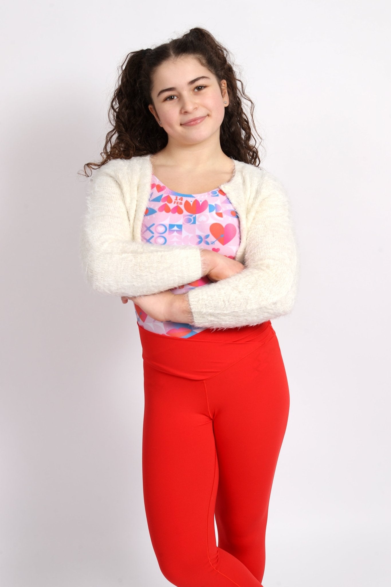 Girl in heart print gymnastics leotard with red leggings and cardigan.