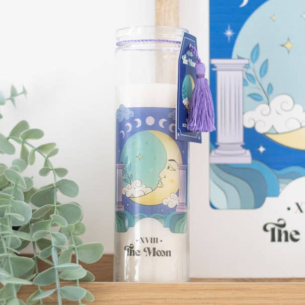 The Moon tarot candle in a tall glass jar with a purple tassel accent.