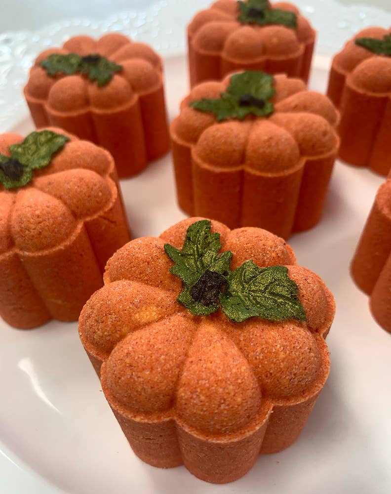 Pumpkin-shaped candies with green leaves on a white plate