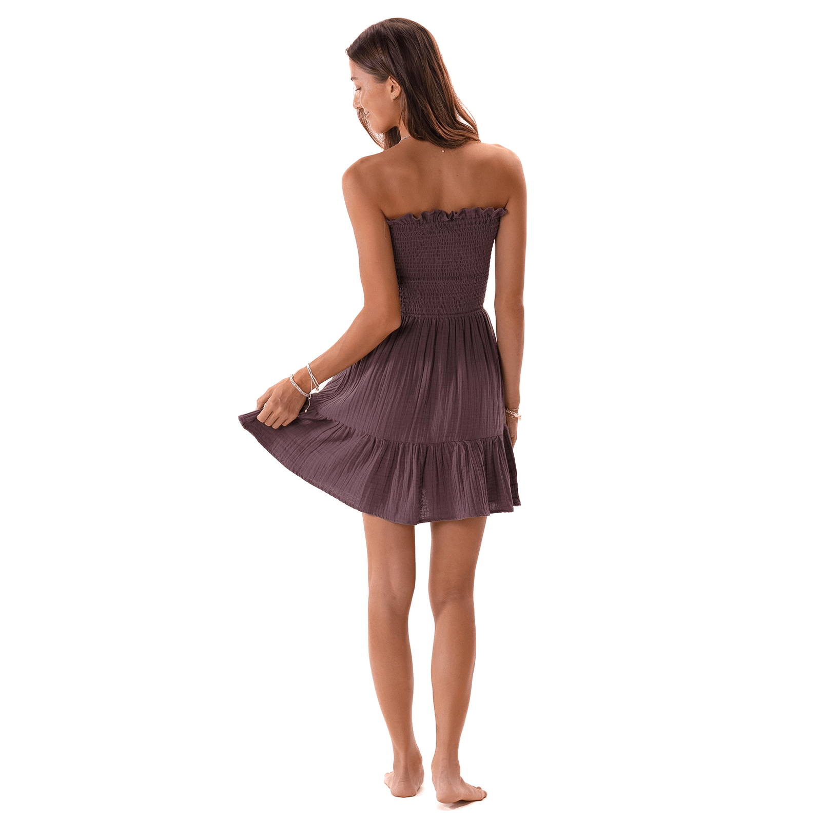 Dark purple crinkle gauze strapless smocked mini dress with ruffled hem on model, back view.