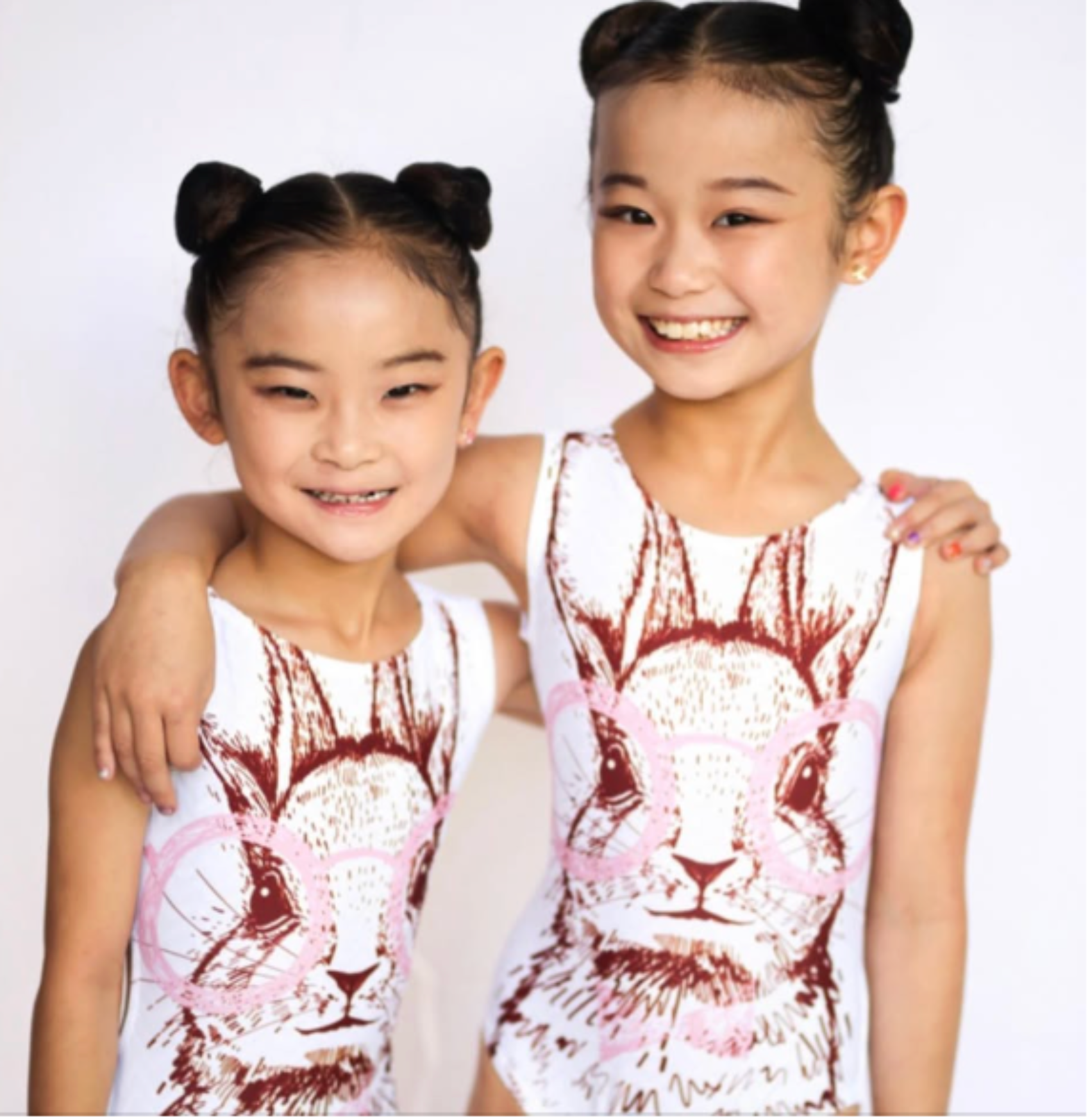 Two children wearing sleeveless bunny leotards with animal prints on a white background