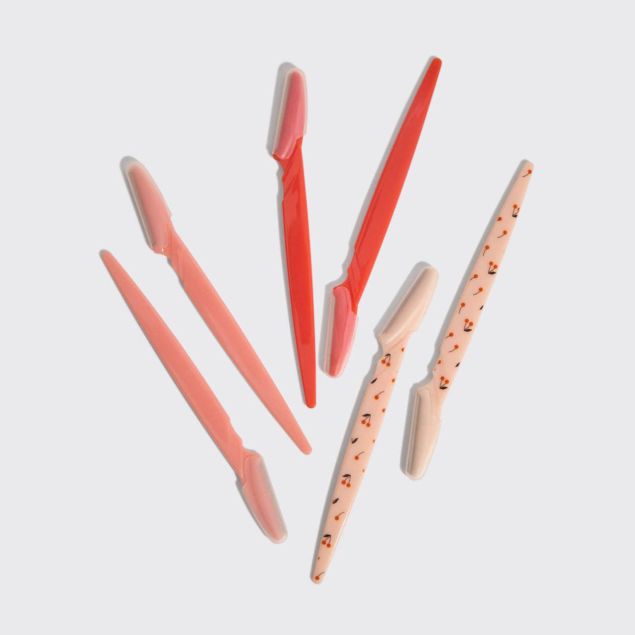 Set of pink and orange makeup brushes on a light gray background