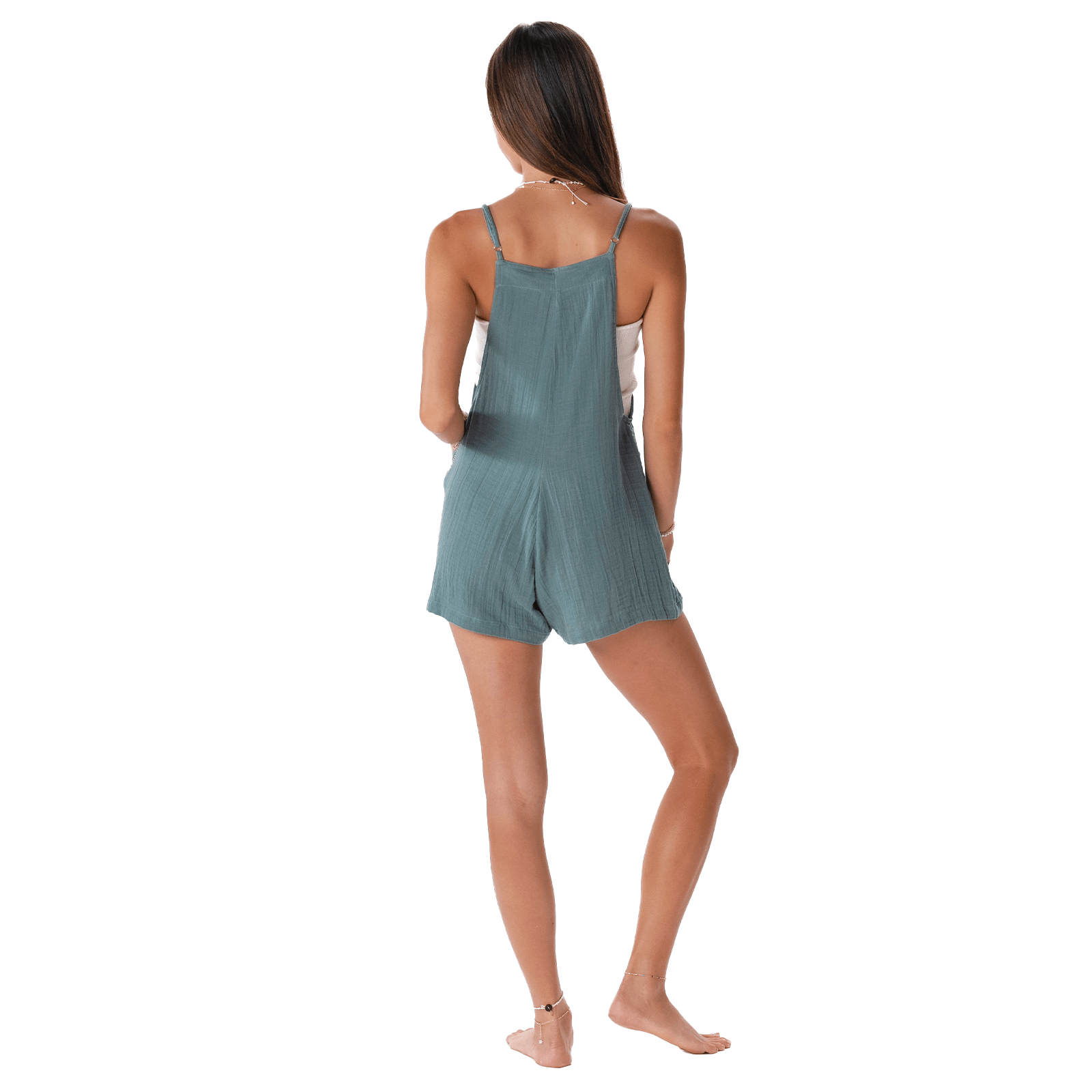 Woman from back wearing a teal crinkle fabric romper with adjustable straps over a white top