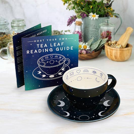 Tea cup and saucer with celestial design on a table with a 'Tea Leaf Reading Guide' book.