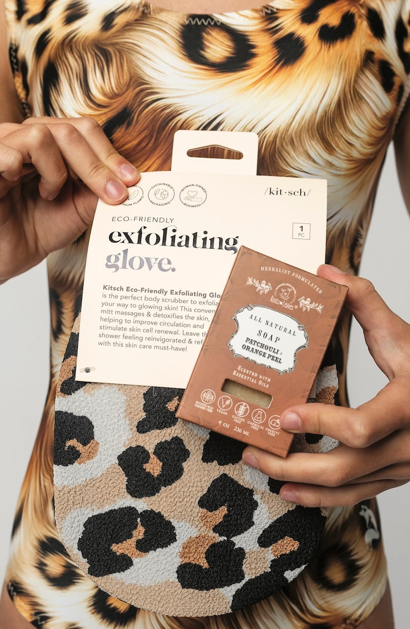 Person holding a Kit-Sci exfoliating glove and a brown box with leopard print background