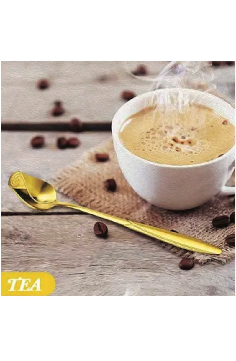 White cup of tea with a gold rose tea spoon on a wooden surface with scattered coffee beans.