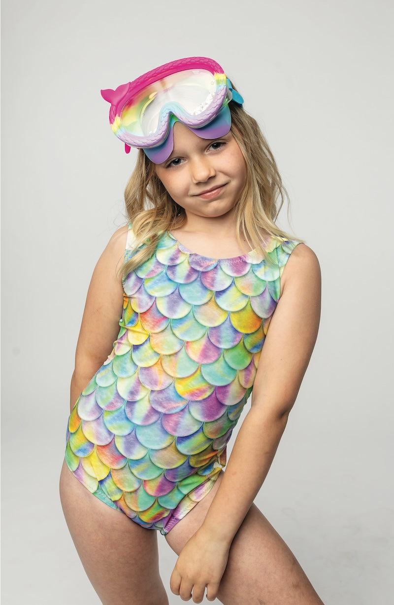 Child wearing a colorful mermaid scale swimsuit with a matching headband on a plain background