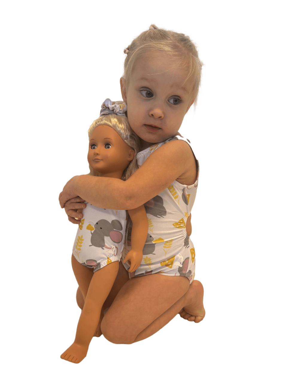 Toddler girl hugging a doll both wearing matching mouse print swimsuits.