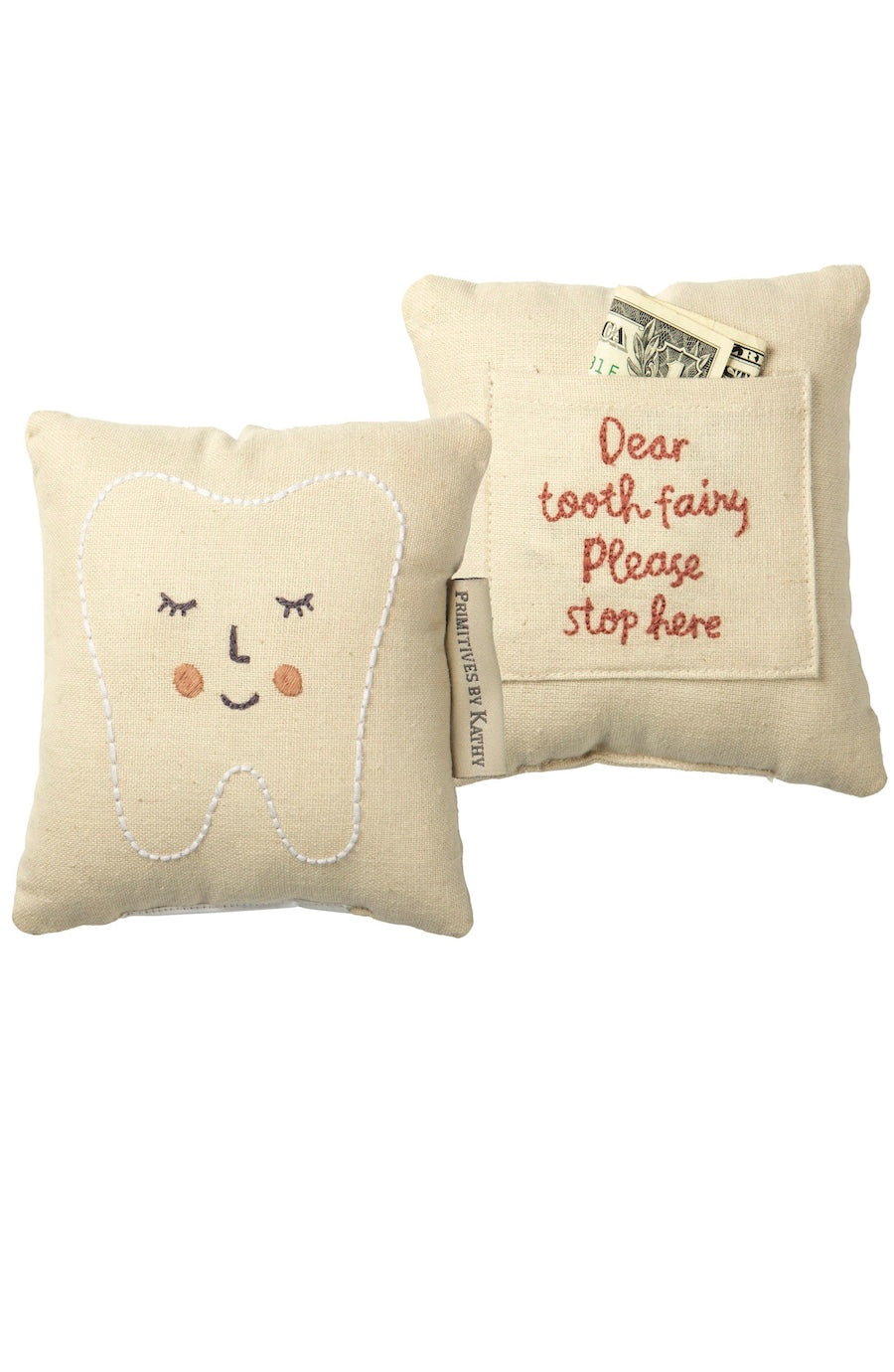 Two small beige fabric tooth-shaped pillows on a white background. One pillow shows a white embroidered tooth face with closed eyes and pink cheeks.