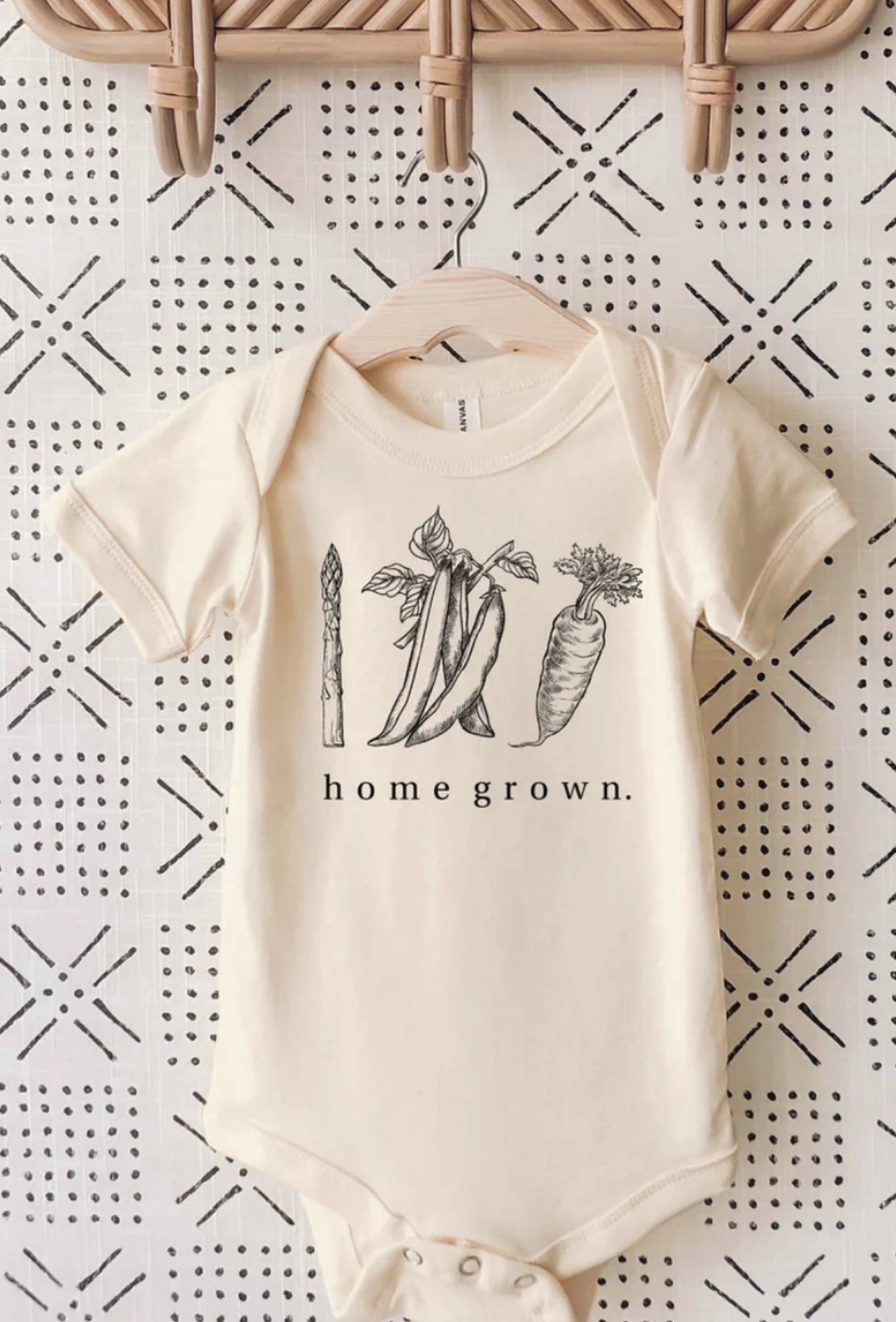 cream-colored baby onesie with image of vegetables on the front and text that says home grown