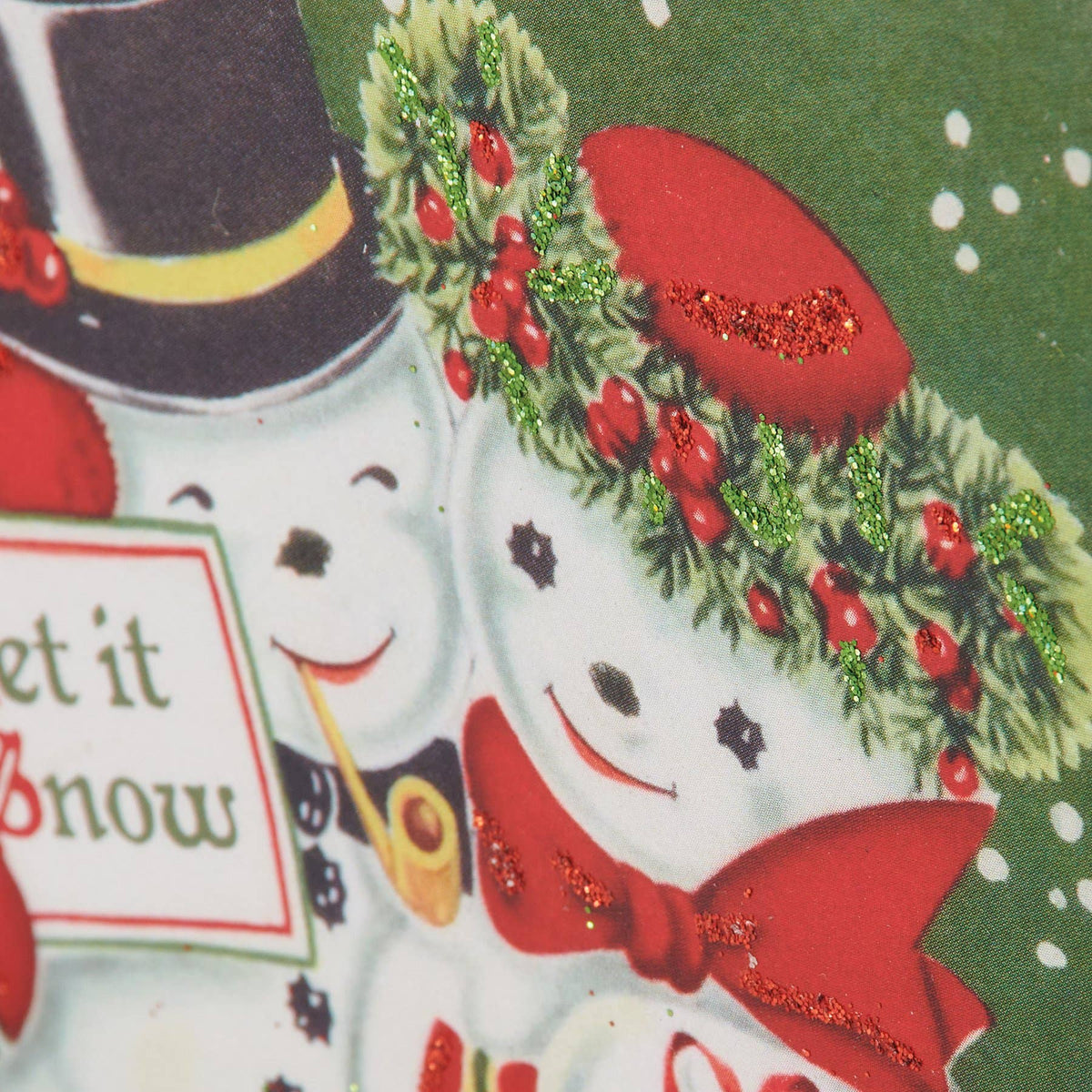 Close-up of a Christmas-themed printed design featuring two snowman faces with red hats, red bow ties, green garland with red berries, and a dark green background with white speckles.