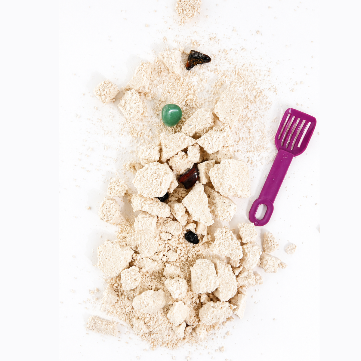 Play sand with toys and a purple spatula on a white background