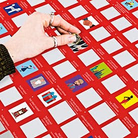 Hand placing a card on a red game board with various small cards featuring images and text.