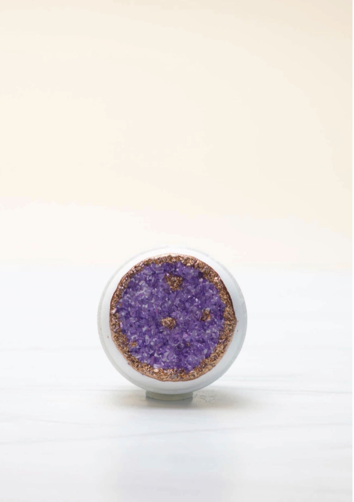 Round decorative item with purple center and white border on a light beige background
