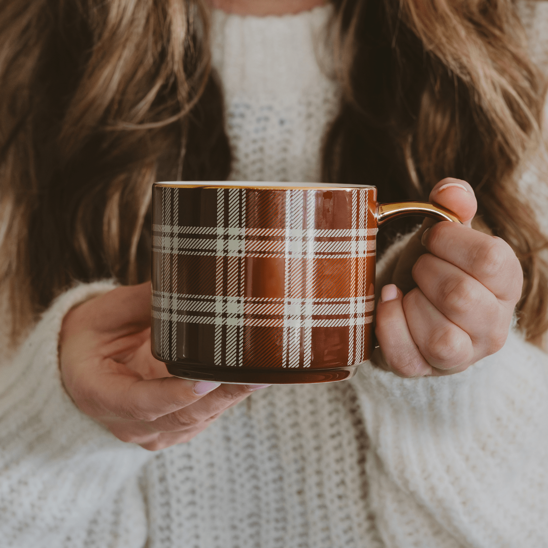 Person holding a plaid mug with a soft focus background