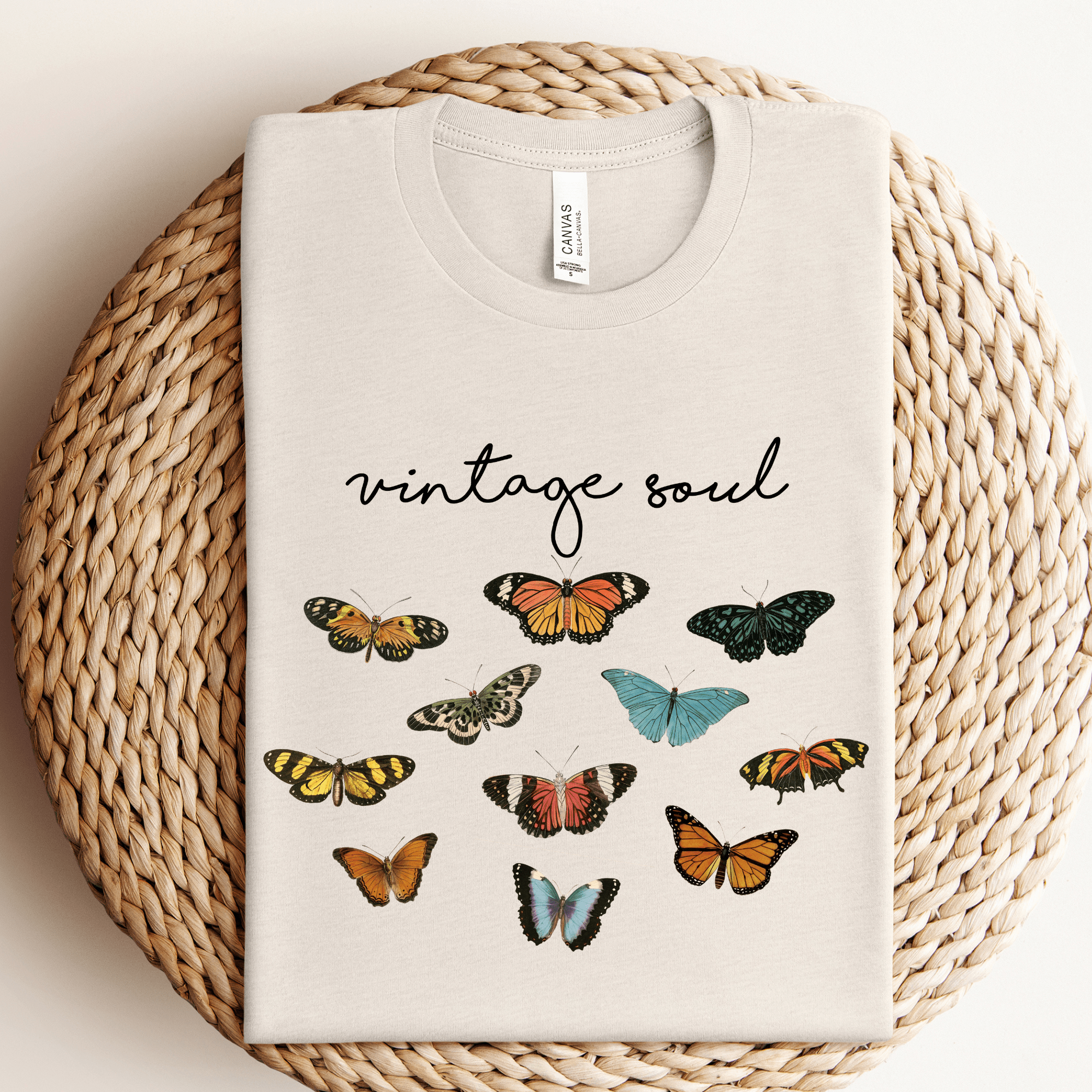 Beige t-shirt with butterfly designs and 'vintage soul' text on a woven surface