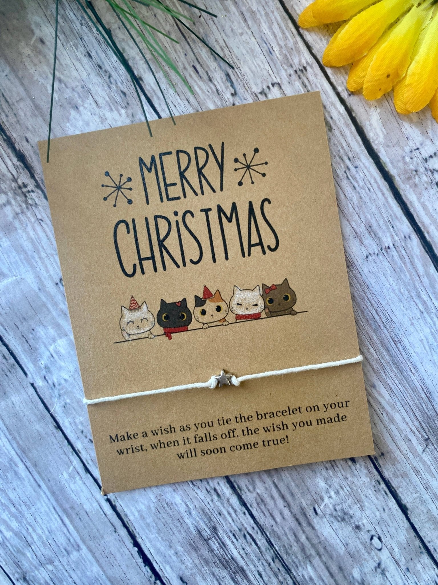 Kraft paper card with cat illustrations and 'Merry Christmas' text on a wooden surface.