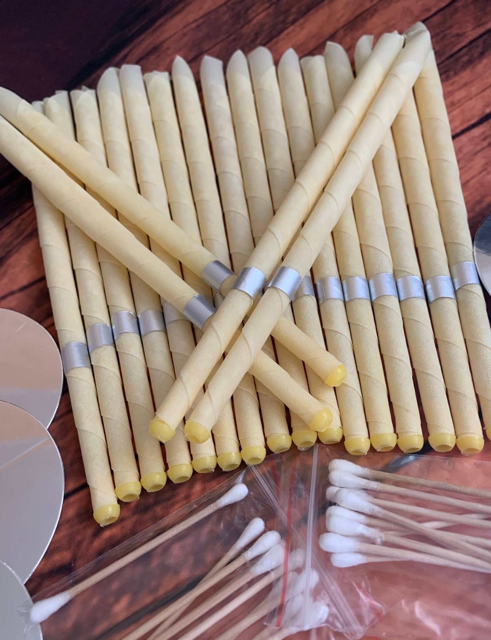 Stack of yellow sticks with silver bands on a wooden surface, with cotton swabs in the foreground.