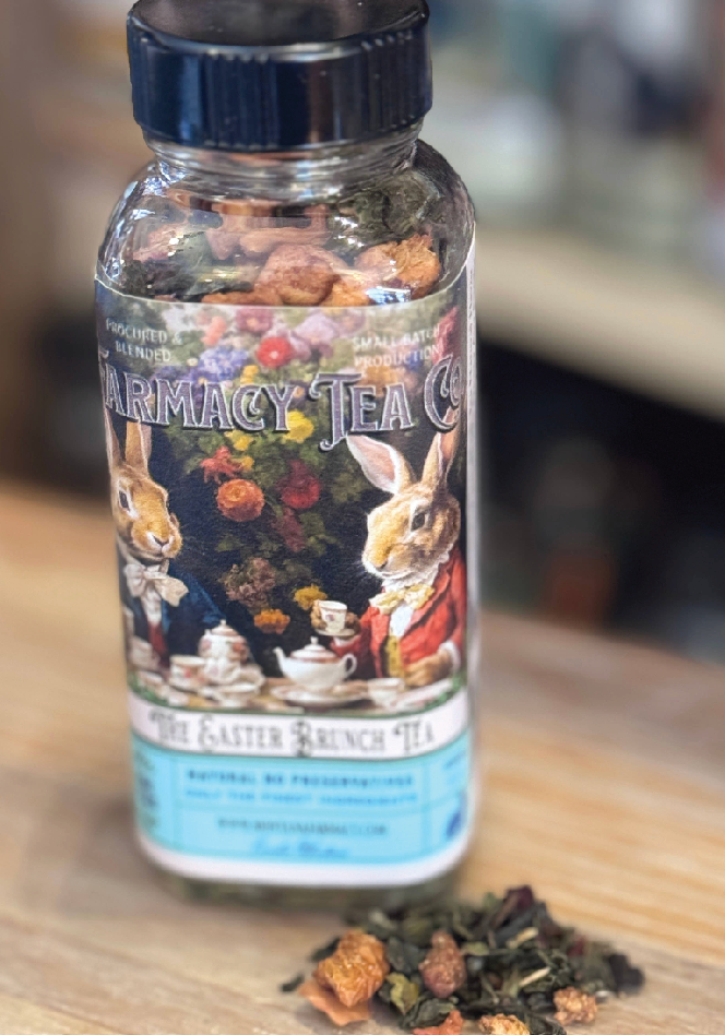 Bottle of 'The Easter Bunny Tea' from Pharmacy Tea Co. on a wooden surface with loose tea leaves.