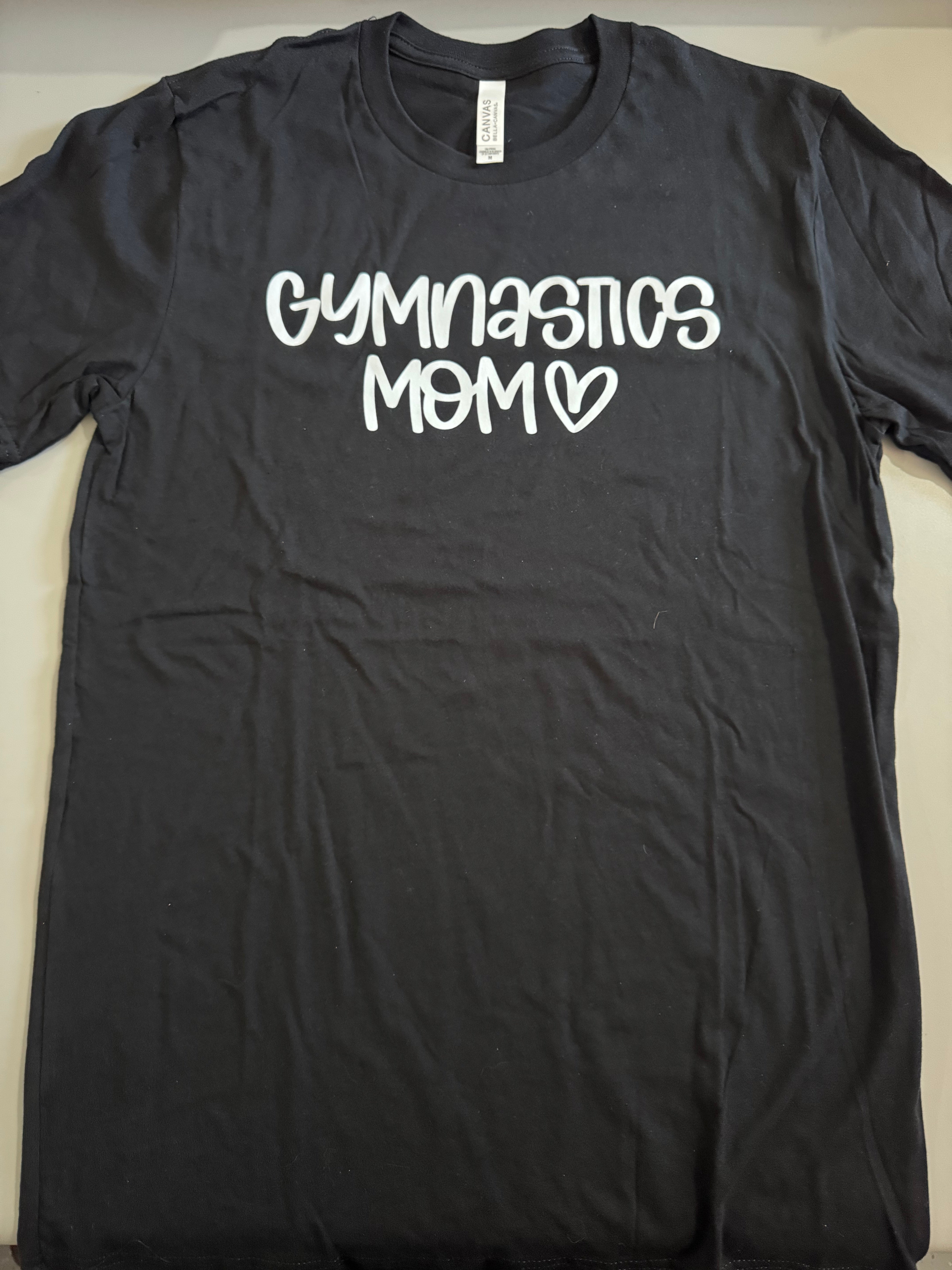 Black t-shirt with 'Gymnastics Mom' text on a white background