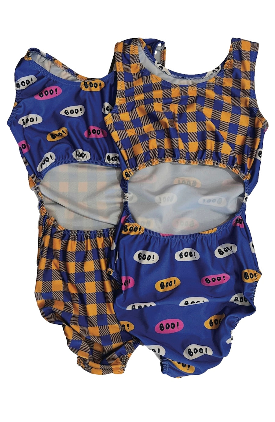 Two Halloween leotards laid flat on a white background. One features a blue and yellow gingham pattern with colorful 'BOO!' speech bubbles, and the other open-back leotard features a blue base with yellow gingham and 'BOO!' bubble prints.