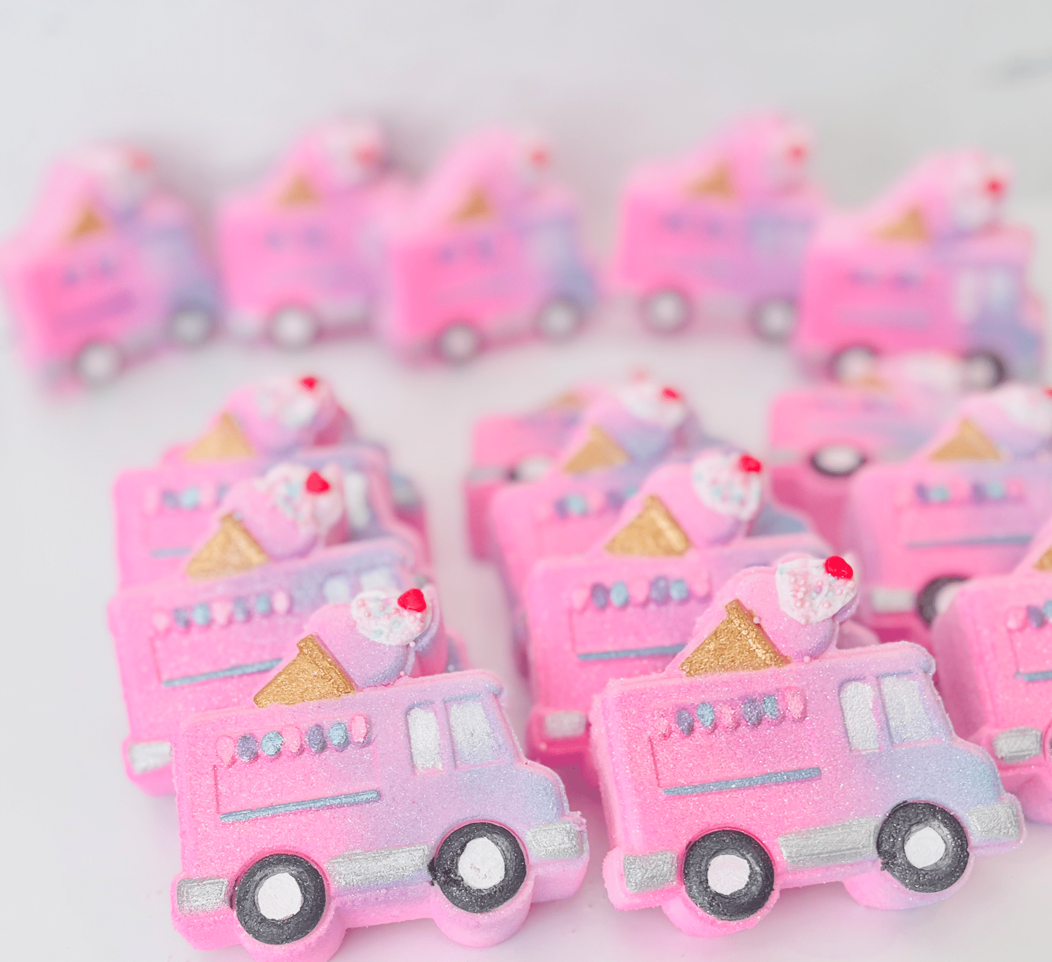 Pink ice cream truck-shaped bath bombs on a white background