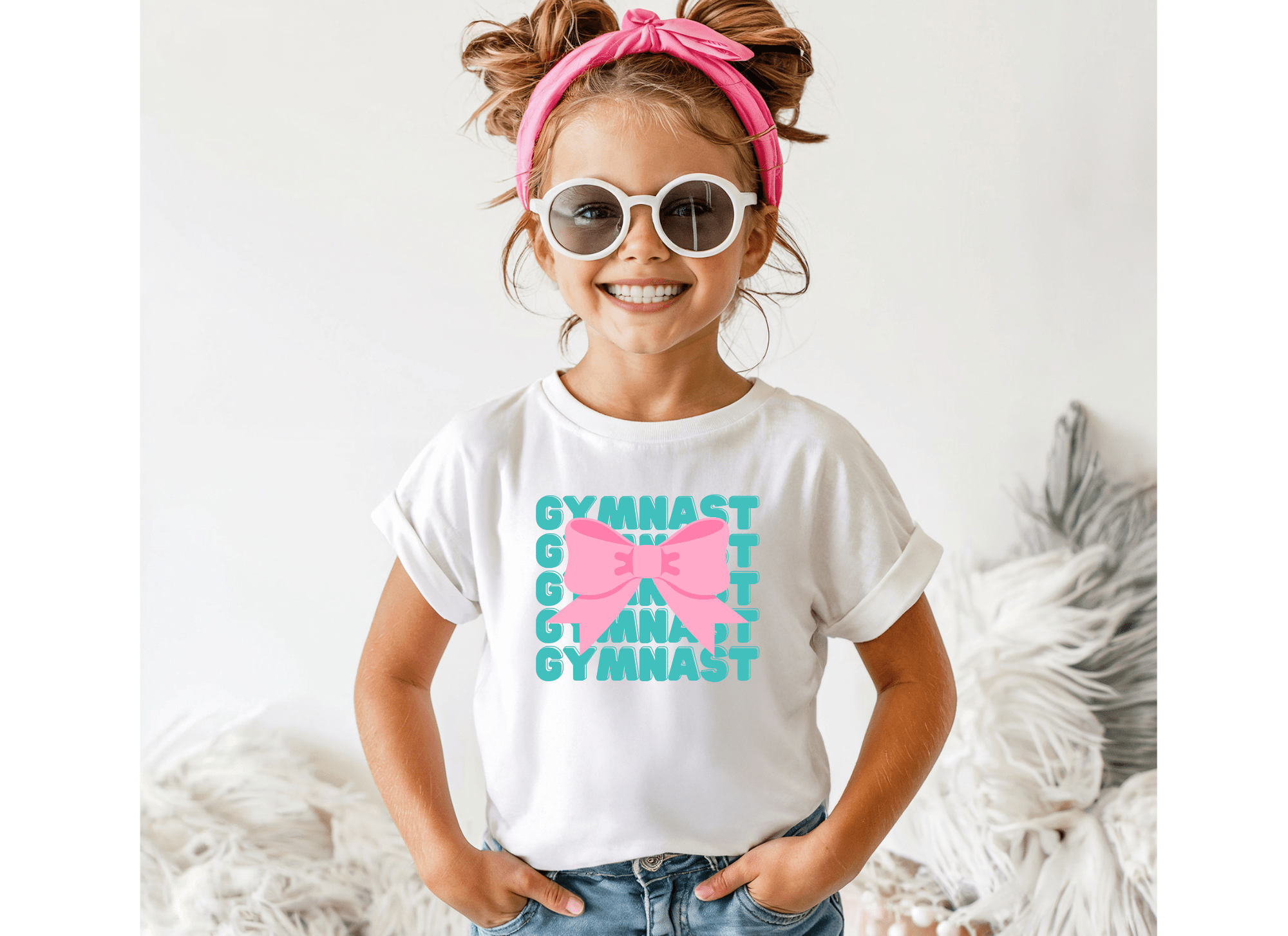 Child wearing a white t-shirt with colorful text and a pink bow, standing against a light background.