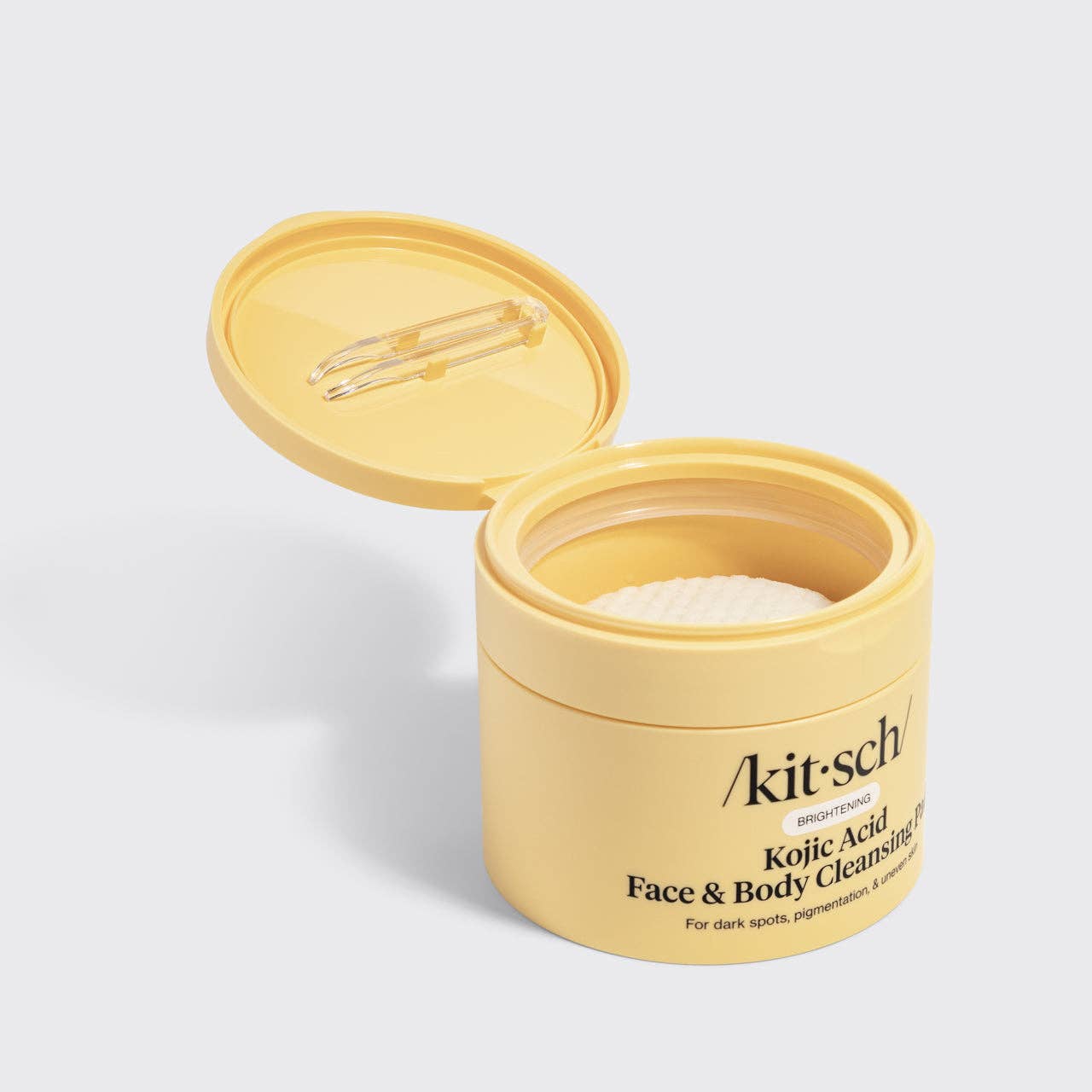 Open yellow jar of Kitsch Kojic Acid Face & Body Cleansing Powder on a light gray background