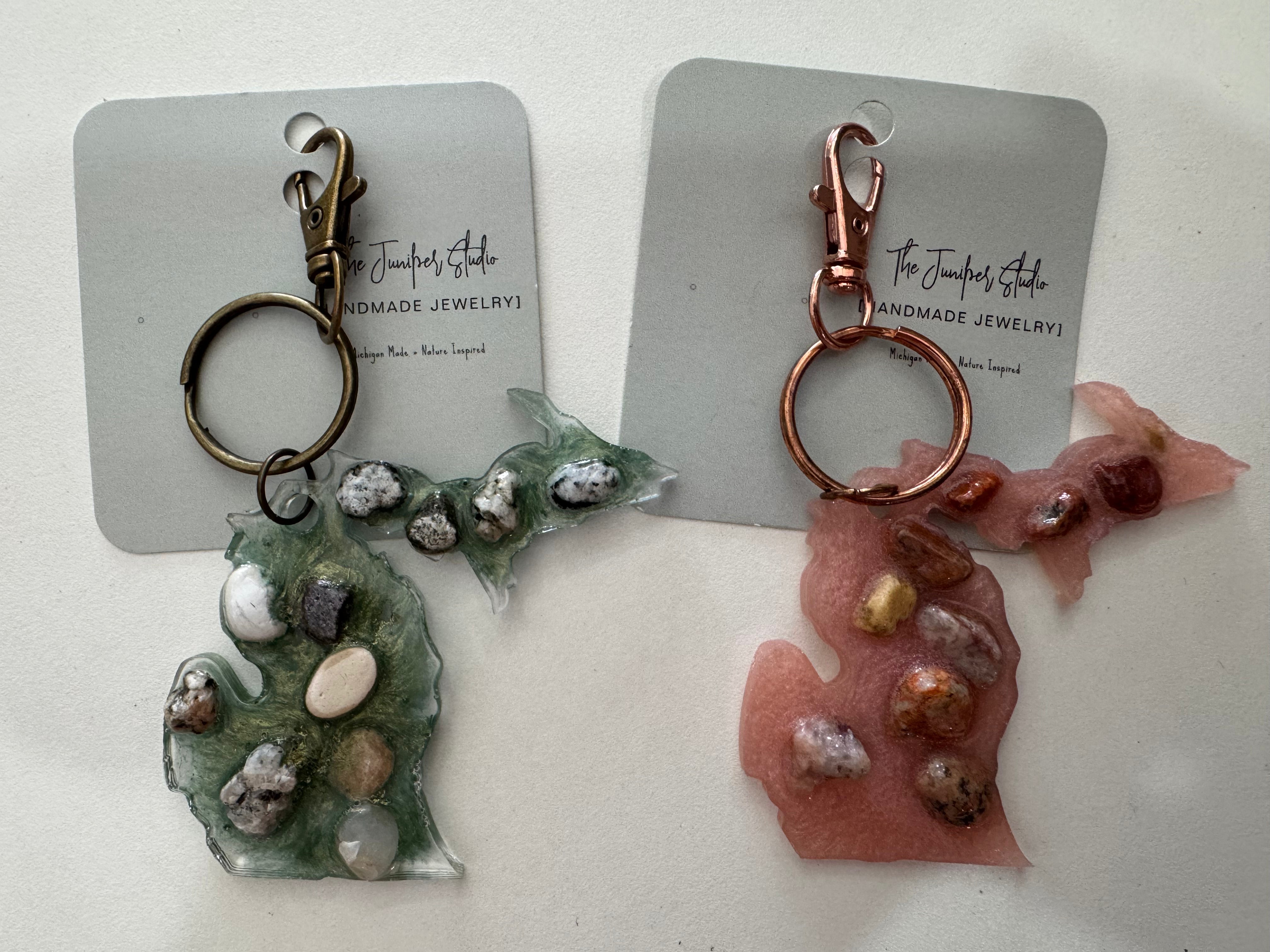 Two keychains with natural stone designs on cards labeled 'The Juniper Studio'.