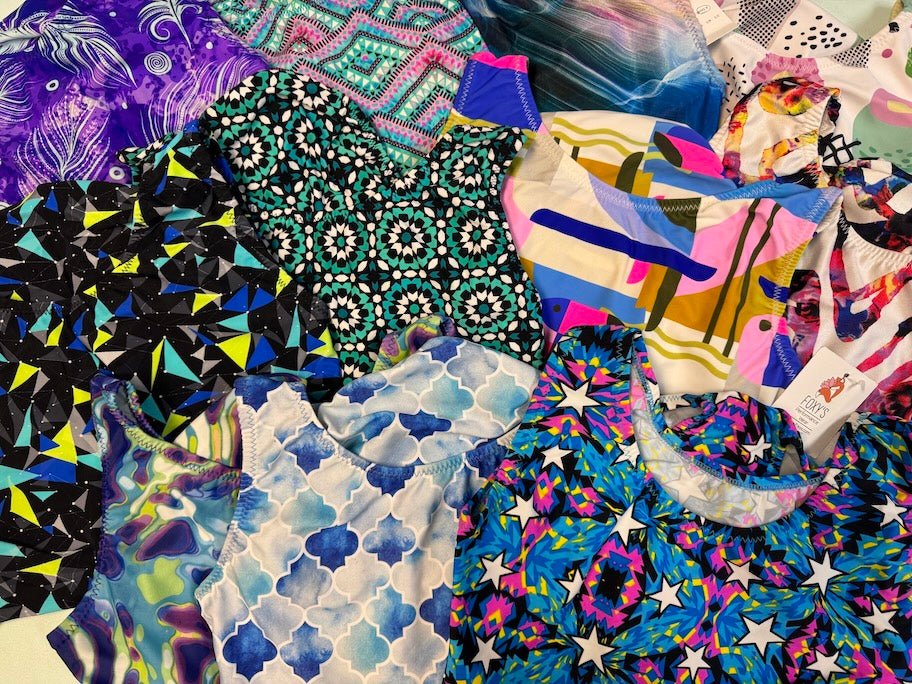 Collection of colorful patterned fabric gymnastics leotards by Foxy's Leotards