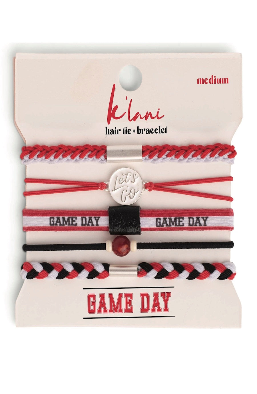 A set of five K'lanı Game Day hair ties and bracelets on a cream-colored cardboard hanger. The set includes red, black, and white braided and striped accessories, with one silver charm engraved 'Let's Go'.