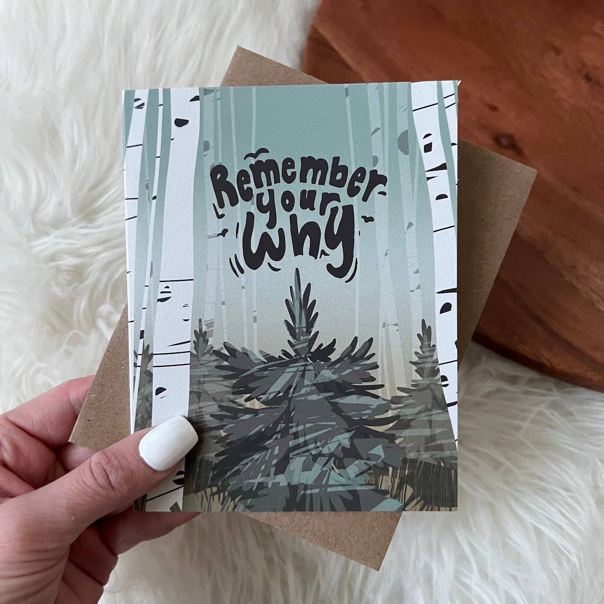 Card with 'Remember your why' text held by a hand on a soft surface