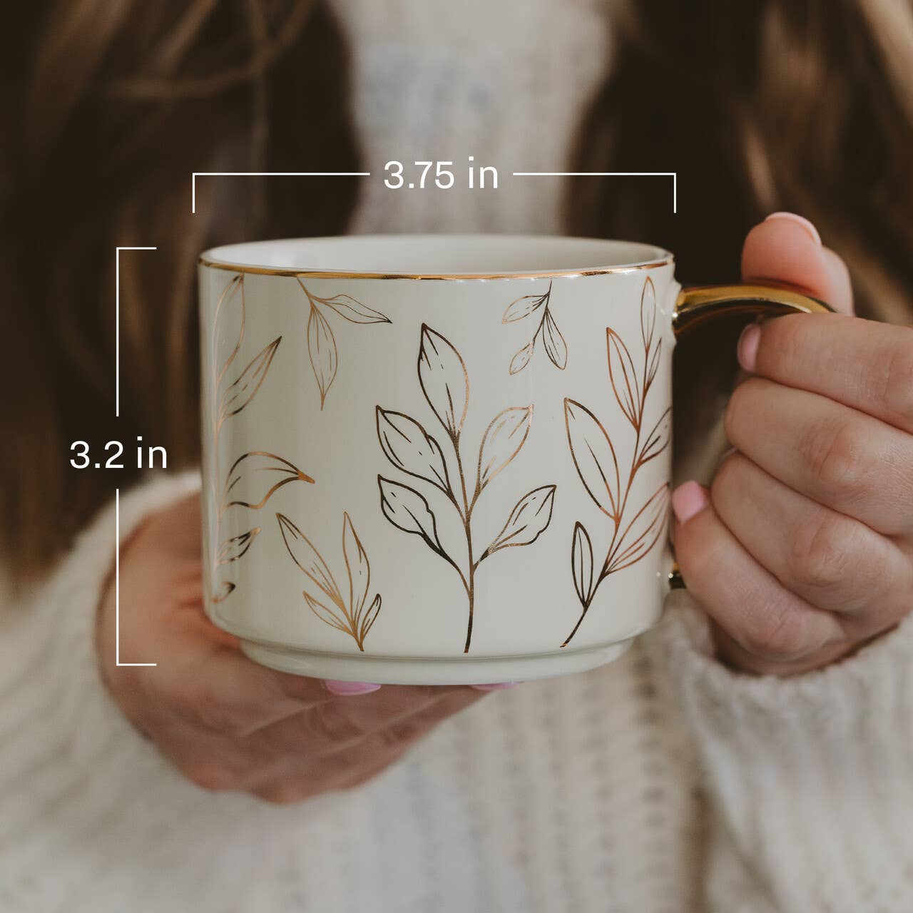 Person holding a mug with leaf patterns and measurements