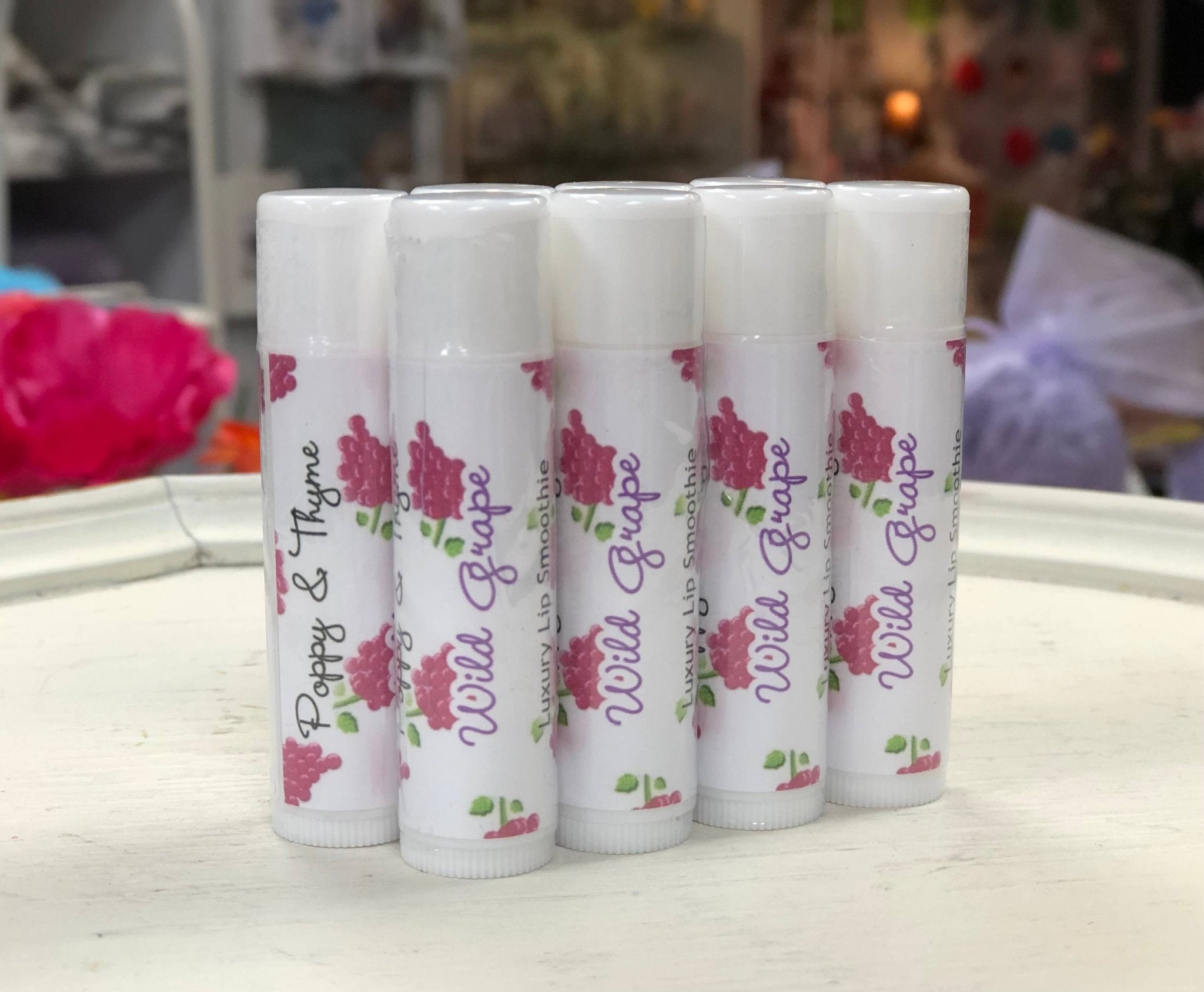 Set of lip balms with floral designs and text on a white surface.