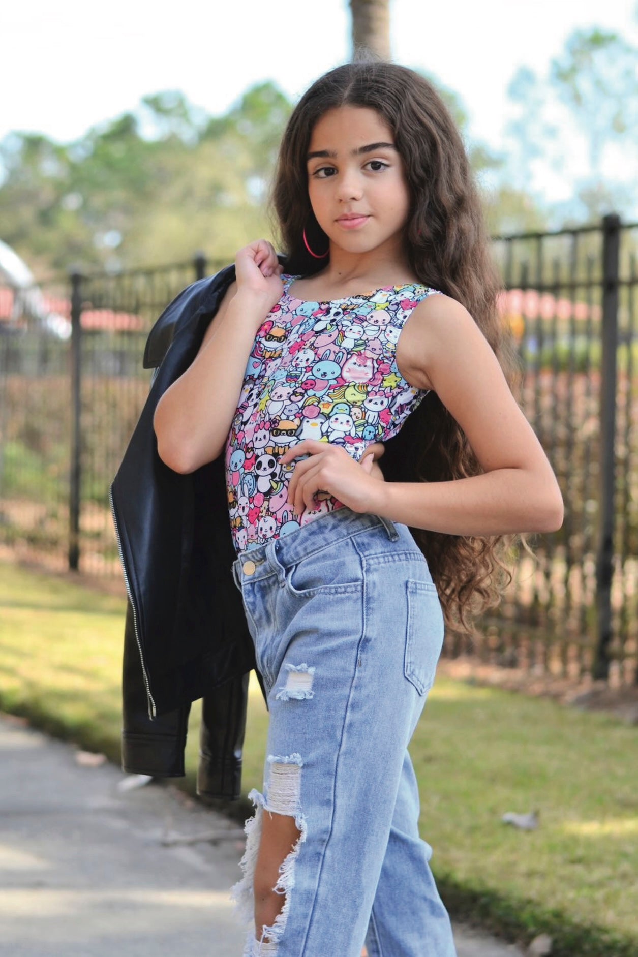 Young woman wearing a cartoon themed gymnastics leotard and ripped jeans outdoors.