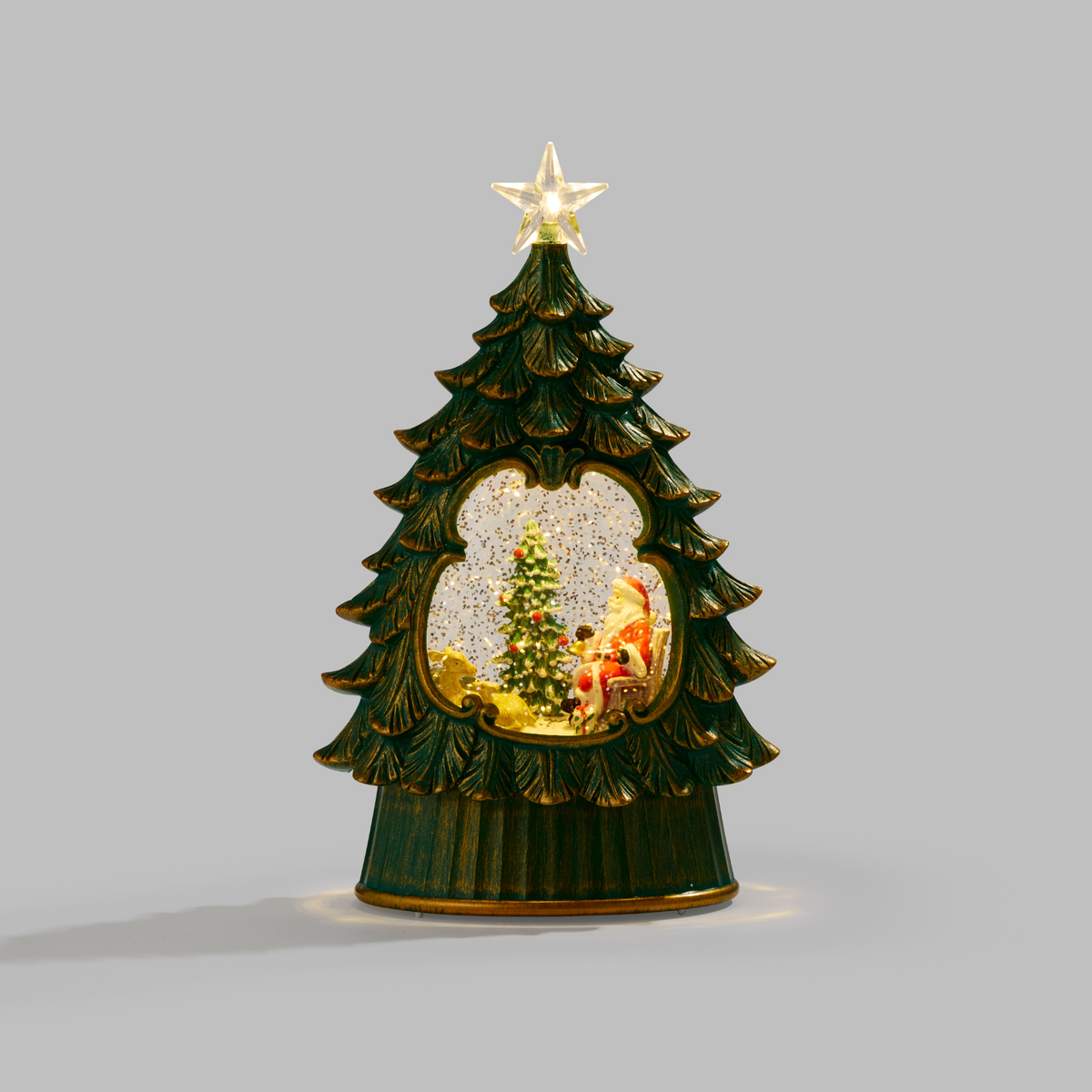 A Christmas tree-shaped decorative figurine with a glowing star on top, a snow globe window showing a miniature Christmas scene, and a dark green body with gold trim, set against a plain gray background.