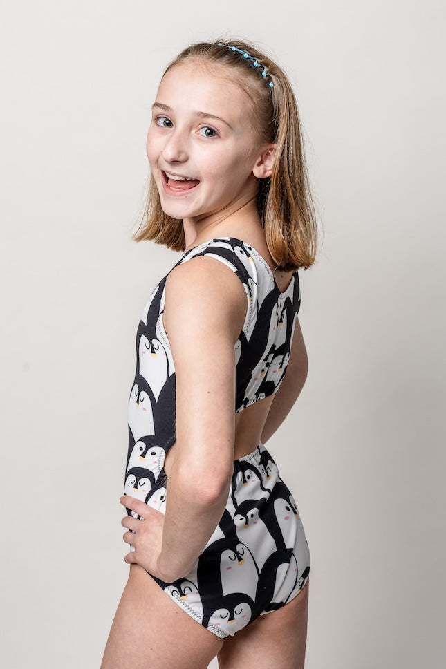 Young girl wearing an ultra soft black and white patterned leotard for girls on a plain background
