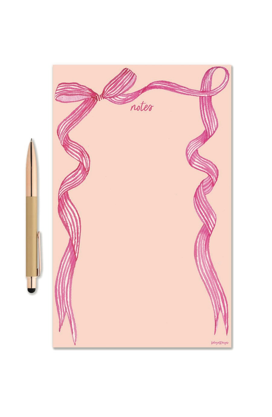 A peach-colored notepad with a pink illustrated ribbon border and the word 'notes' printed near the top, shown next to a gold pen on a white background.