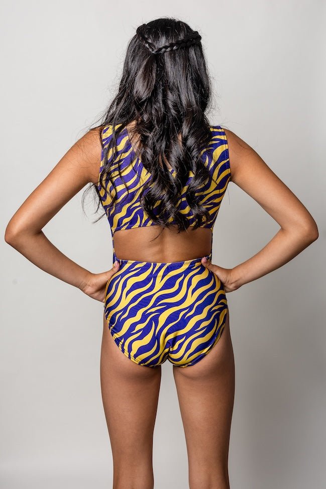 gymnast wearing a purple and yellow zebra striped gymnastics outfit on a plain background
