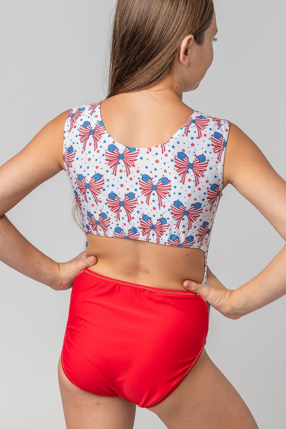 gymnastics leotard with bow pattern and an open-back tank design with red bottom